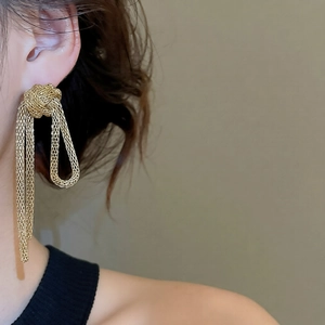 Detailed close-up of golden mesh knot tassel earrings worn on model for modern style