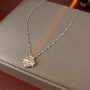 Macro detail of guilloché four-leaf clover pendant necklace with zircon stone inlay
