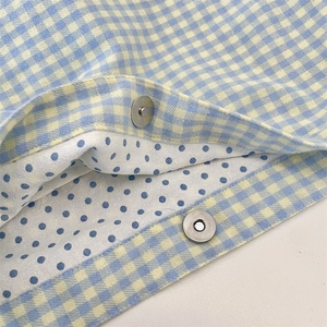 Detail of blue and yellow plaid canvas bag with magnetic clasp and polka dot lining