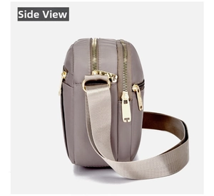 Side view of gray nylon crossbody bag showing multiple zip layers and gold metal hardware