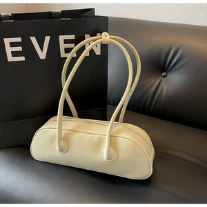 Close-up of minimalist cream large underarm bag on a black leather background
