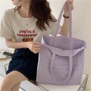 Detailansicht der fliederfarbenen Stofftasche mit lila Stickerei und robuster Textur des Stoffs