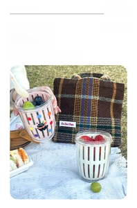 Outdoor picnic scene showing a portable fruit cup with inner drainage basket and cat pattern