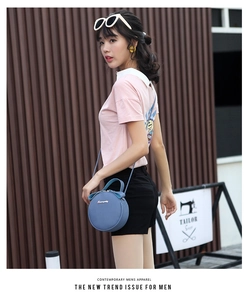 Detail of light blue round crossbody bag with litchi texture and gold metal logo