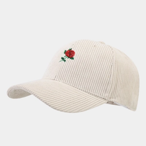 Detailed close-up of red rose embroidery on a cream corduroy baseball cap texture