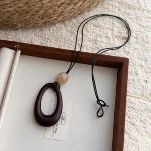 Detail of vintage oval wood resin pendant with bead in a jewelry gift box display