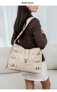 Rear view of a model wearing a stylish cream PU crossbody bag with metal buckles