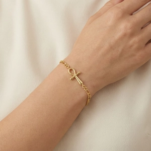 Detailed shot of golden Ankh cross bracelet on wrist with elegant Figaro chain texture