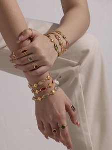 Close-up of a model wearing colorful gemstone heart bracelets and gold stackable rings
