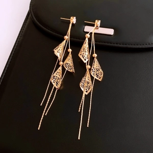 Detail view of 18K gold plated tassel earrings with hollow cone drop on black leather