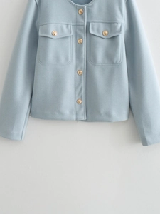 Detail of light blue tweed jacket showing textured fabric and embossed metal buttons