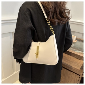 Detail of a white hobo bag featuring gold buckle closure and chain link shoulder strap