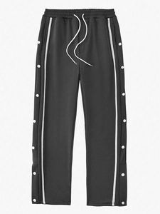Detail of dark grey joggers featuring side metal snap buttons and white stripe accents