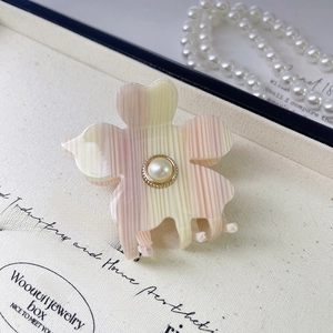 Detail of flower hair claw clip with acetate finish and pearl center on canvas box