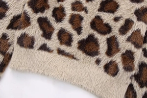 Nahaufnahme des flauschigen Strickmaterials mit Leopardenmuster und Rippbündchen am Saum