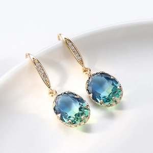 Macro shot of oval blue-green gemstone drop earrings with gold-plated zircon setting