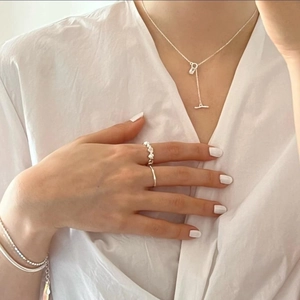 Close-up of minimalist 925 sterling silver geometric zircon necklace on white shirt