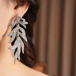 Close-up of vintage silver leaf earrings with sparkling rhinestones worn by a model
