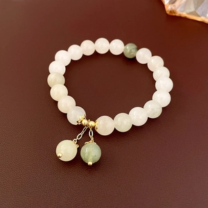 Detail of beaded stone bracelet featuring white-green beads and gold ball pendants