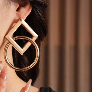 Gros plan d'une boucle d'oreille géométrique en or avec des formes carrées et rondes