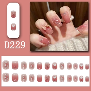 Close-up of pink gradient press-on nails with 3D bows and silver glitter accents