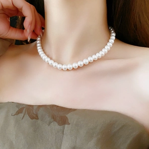 Gros plan d'un collier choker en perles blanches porté au cou d'un mannequin