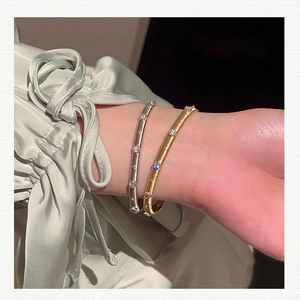 Macro shot of gold and silver brushed bangles with zircon accents on satin background