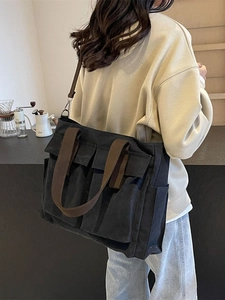 Borsa tote in tela nera con tasche multiple mostrata in un ambiente raffinato da bar