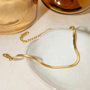 Detailed close-up of 18K gold-plated stainless steel snake chain anklet with lobster clasp