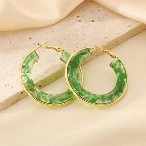Golden rimmed green marble texture resin hoop earrings on a stone surface