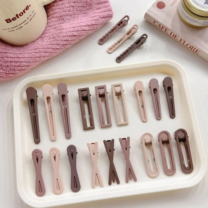 Flat lay of multiple coffee-colored seamless hair clips including pointed and square styles