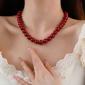 Elegant red beaded necklace with round cinnabar beads on female model in lace dress
