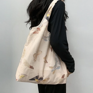 Detail of canvas tote bag with vintage butterfly prints shown on a model's shoulder