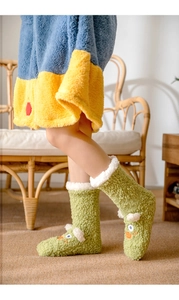 Detail of green plush frog socks with white fuzzy trim and cute cartoon eye design