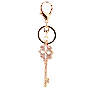 Golden four-leaf clover metal keychain with sparkling rhinestones on white background