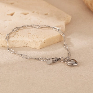 Detailed view of silver stainless steel chain bracelet with heart and round charm on stone