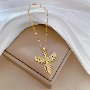 Close-up of a gold phoenix necklace with crystals resting on elegant white silk