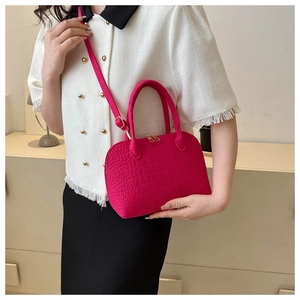 Detailed view of rose red felt shell bag with stone texture and golden hardware