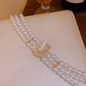 Détail d'un collier de perles multicouches avec pendentif ovale en cristal et monture dorée