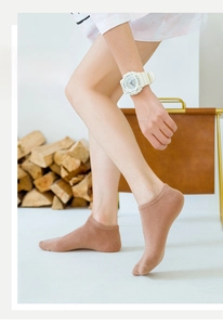 Detail of light coffee knitted ankle socks with ribbed cuffs on model in warm studio setting