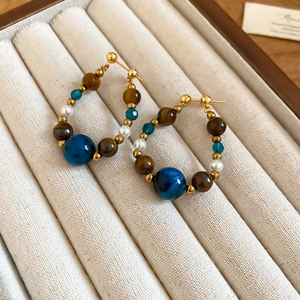 Detail showing vintage gold hoop earrings with tiger eye beads and drop pearls in a box
