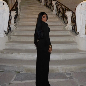 Detail of elegant black turtleneck long dress with sleek side profile on classic stone stairs