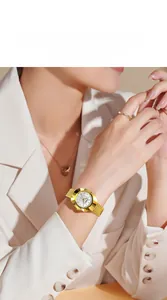 Elegant gold ladies watch with white dial and metal strap worn by a model in a suit
