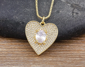 Close-up of gold-plated heart pendant with sparkling cubic zirconia on dark background