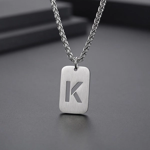 Vue détaillée du pendentif lettre K argenté avec texture brossée et chaîne tressée