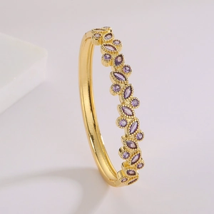 Elegante brazalete bañado en oro de 18K con circonitas púrpuras visto desde un ángulo de 45 grados
