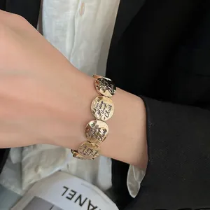 Golden round metal charm bracelet with motivational engraving on black suit sleeve