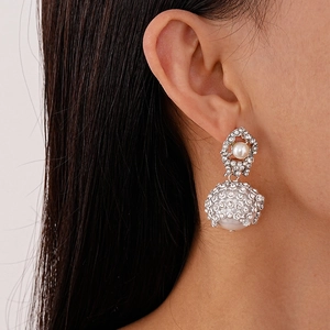 Detail of luxury rhinestone mesh drop earrings with large pearls on female model