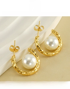 Detailed macro view of gold hammered titanium steel earrings with round white pearl inlay
