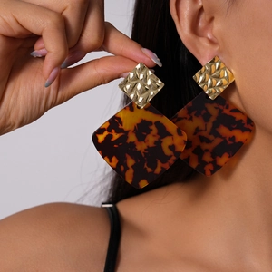Elegant geometric tortoiseshell acrylic drop earrings with gold metallic accents on model